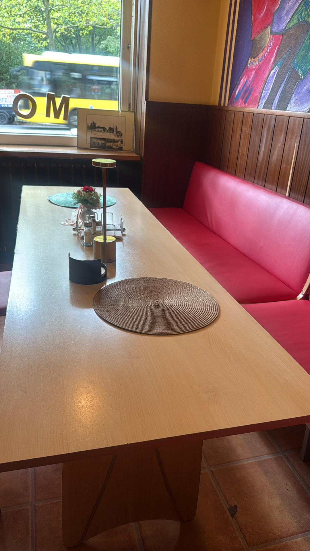 Long wooden tables and red bench seating inside the restaurant